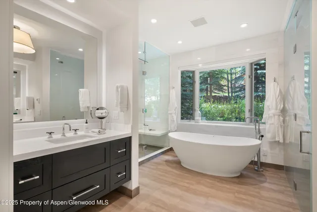 a bathroom with a double vanity sink large mirror and bathtub