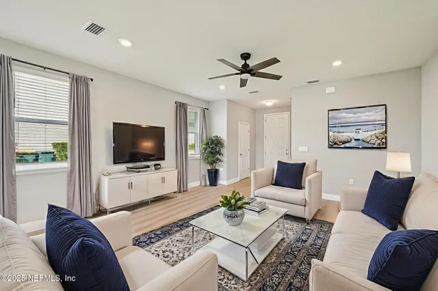 a living room with furniture a flat screen tv and a window