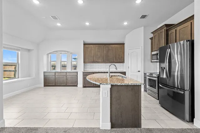 a kitchen with stainless steel appliances granite countertop a refrigerator a stove and a sink