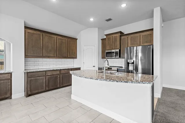 a kitchen with stainless steel appliances granite countertop a sink refrigerator and microwave