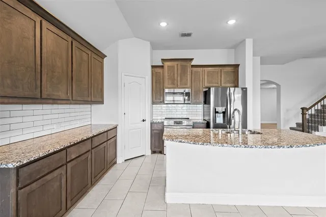 a large kitchen with granite countertop a sink and cabinets