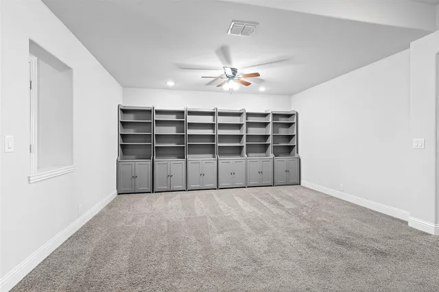 an empty room with a ceiling fan closet and windows