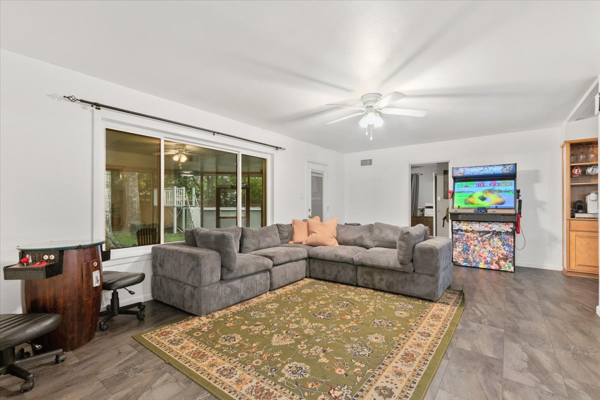 607 Short Street Smithville, TX 78957 - Photo 5 of 31 Spacious living area featuring dark wood-finish flooring, white walls, and a ceiling fan with integrated lighting