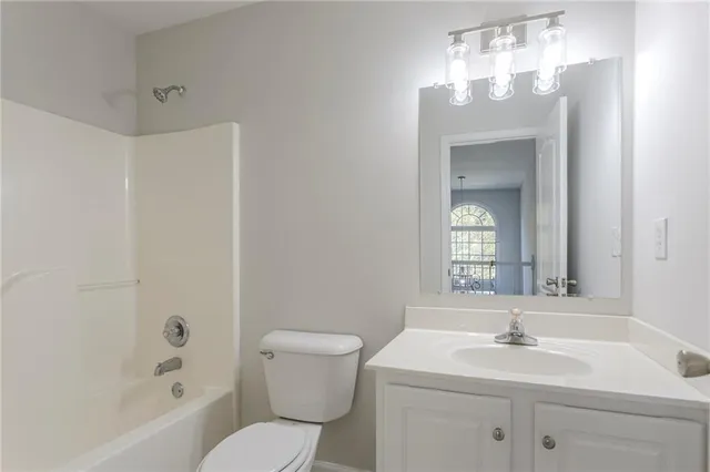 a bathroom with a toilet a sink a mirror a bathtub and vanity