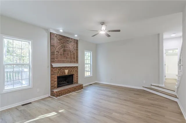 an empty room with windows fireplace and wooden floor