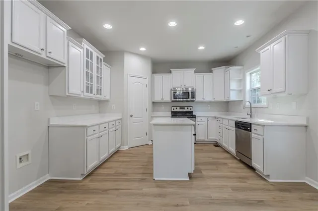 a kitchen with white cabinets appliances a sink and a counter top space
