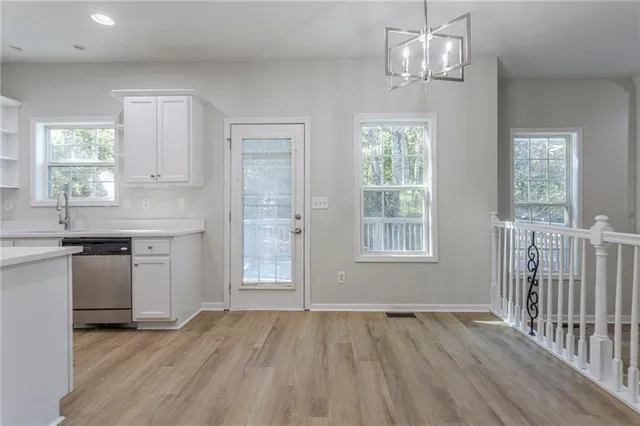 a kitchen with stainless steel appliances granite countertop a stove a sink dishwasher a refrigerator and a dining table with wooden floor