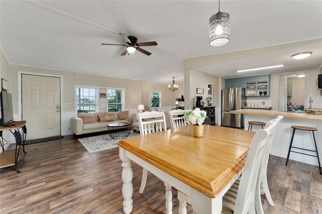15305 Northwest 112th Place Road Morriston, FL 32668 - Photo 47 of 95 a dining room with wooden floor a chandelier a glass table and chairs