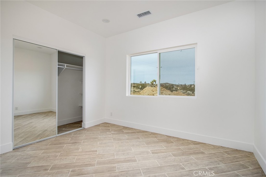 62474 Golden Street Joshua Tree, CA 92252 - Photo 26 of 31 an empty room with wooden floor and windows
