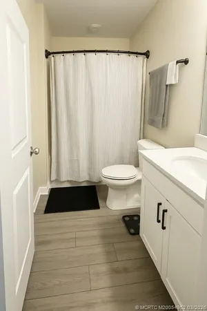 a bathroom with a sink a toilet a window and a shower