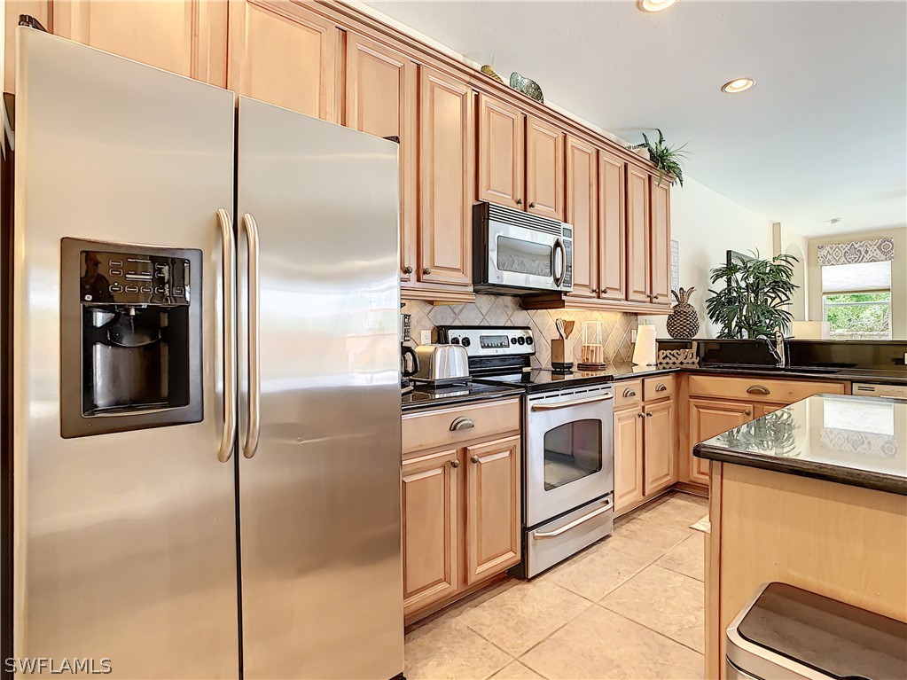 2816 Via Piazza Loop Fort Myers, FL 33905 - Photo 8 of 34 a kitchen with stainless steel appliances granite countertop a refrigerator a stove and a sink with wooden floor