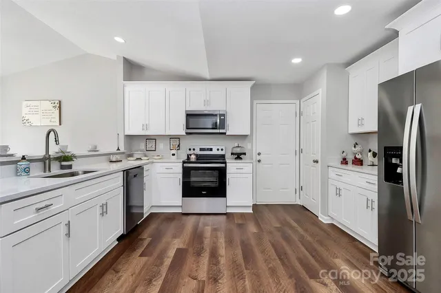 a kitchen with a refrigerator a stove top oven a sink dishwasher and wooden floor