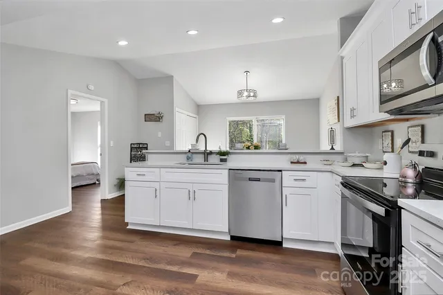a kitchen with stainless steel appliances granite countertop a sink a stove a refrigerator and cabinets