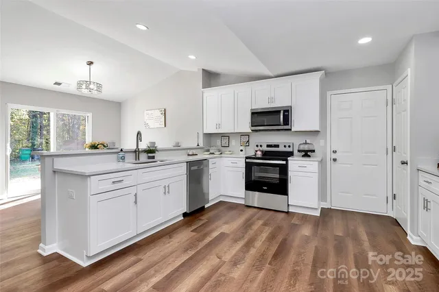 a kitchen with granite countertop white cabinets and stainless steel appliances