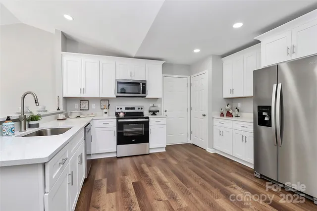 a kitchen with white cabinets sink and stainless steel appliances