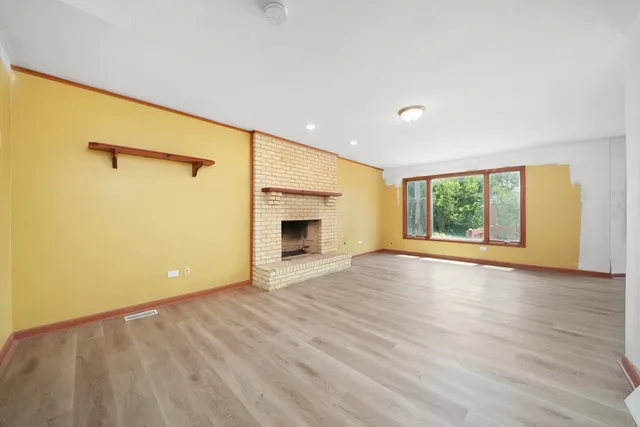 a view of an empty room with a window and a fireplace