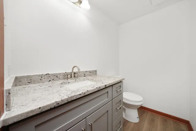 a bathroom with a granite countertop sink and a toilet