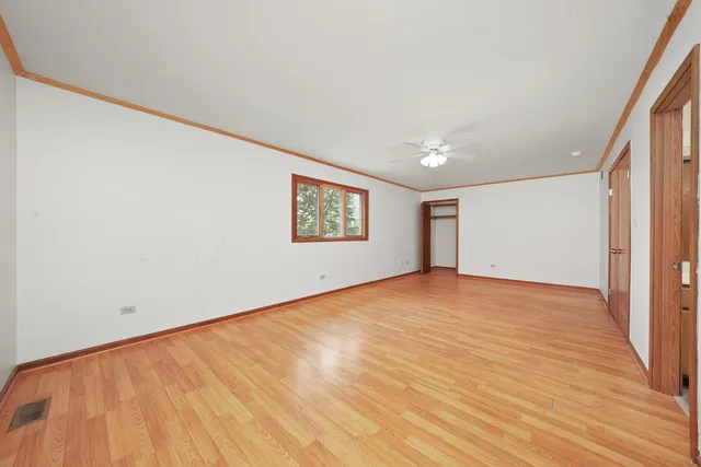 a view of an empty room with window and wooden floor