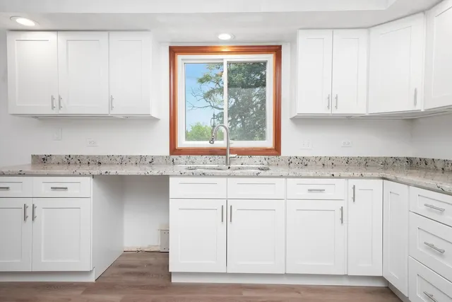 a kitchen with granite countertop white cabinets and a window