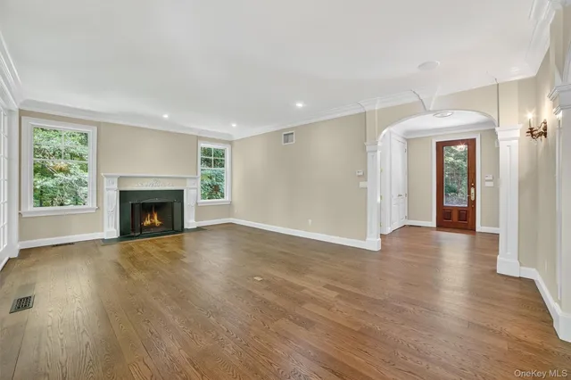 a view of an empty room with wooden floor fireplace and a window