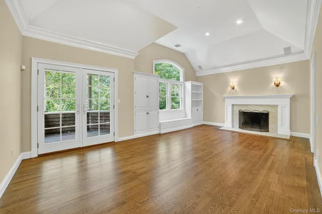 an empty room with wooden floor fireplace and windows