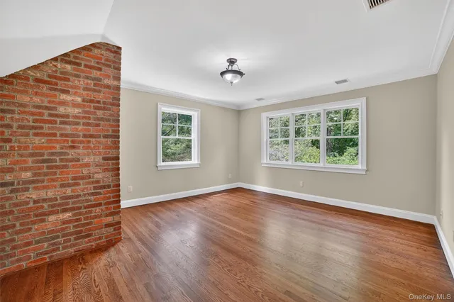 an empty room with wooden floor chandelier fan and windows