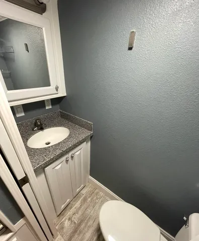 a bathroom with a granite countertop sink toilet and a mirror