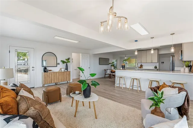 a living room with furniture kitchen view and a chandelier