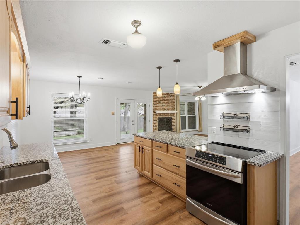 209 Valley View Court Azle, TX 76020 - Photo 13 of 39 Kitchen featuring stainless steel range with electric cooktop, light stone countertops, light wood-style flooring, hanging lights, and french doors