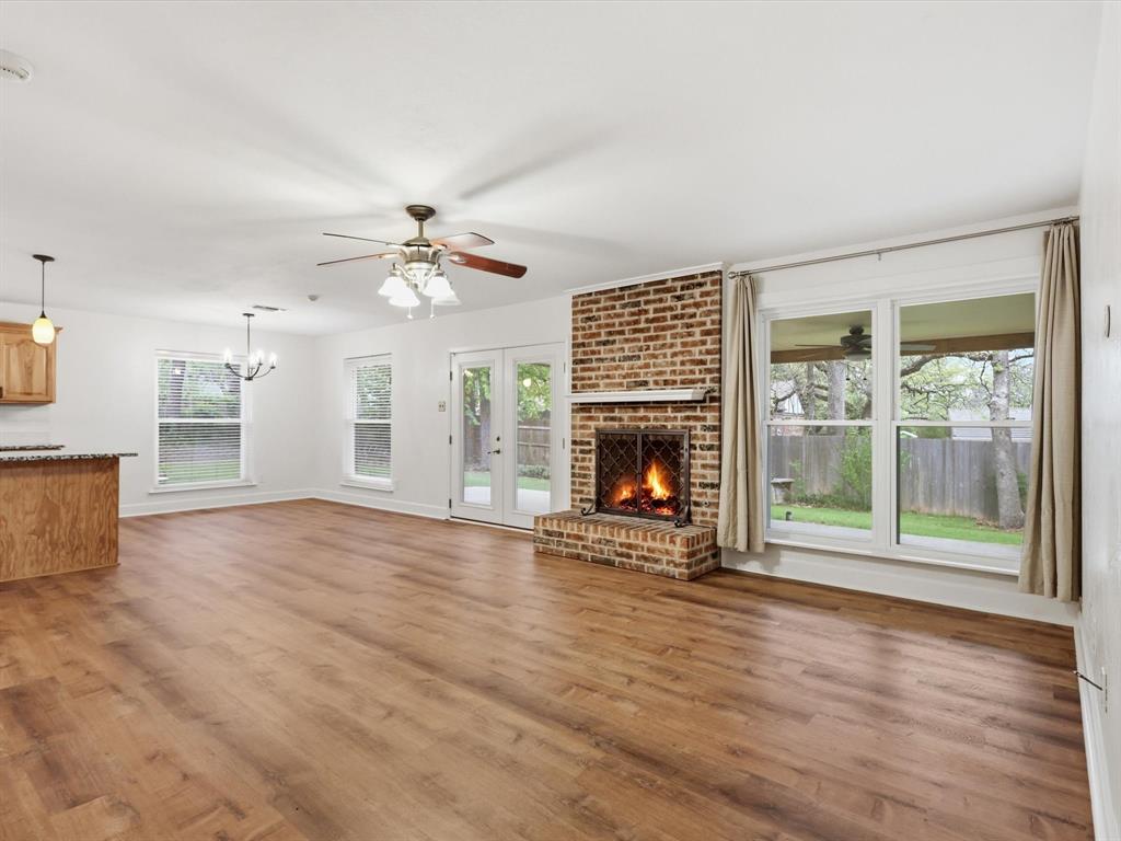 209 Valley View Court Azle, TX 76020 - Photo 16 of 39 Unfurnished living room featuring a fireplace, ceiling fan, suspended lighting, and light wood-style floors