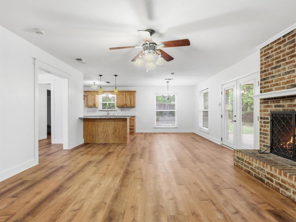 209 Valley View Court Azle, TX 76020 - Photo 17 of 39 Unfurnished living room with a ceiling fan, a brick fireplace, and light wood-style flooring