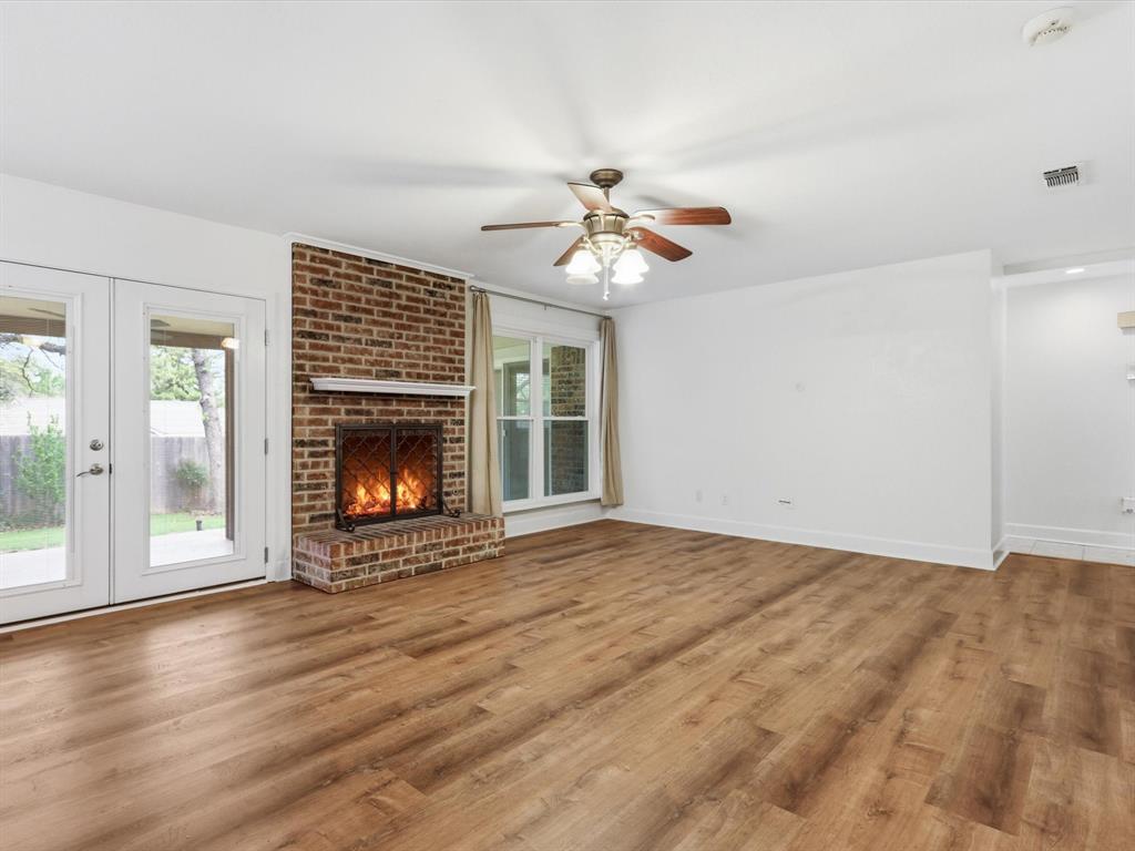 209 Valley View Court Azle, TX 76020 - Photo 20 of 39 Unfurnished living room featuring wood finished floors, a ceiling fan, french doors, and a brick fireplace