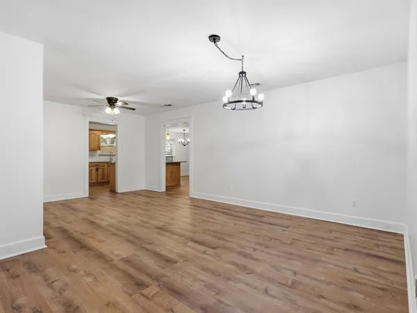 a view of empty room with wooden floor and kitchen
