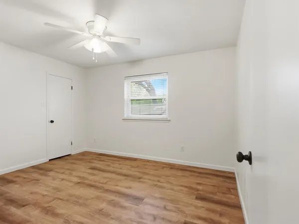 an empty room with a chandelier fan and windows