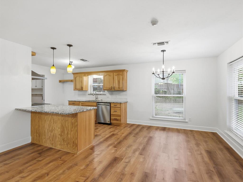 209 Valley View Court Azle, TX 76020 - Photo 7 of 39 Kitchen featuring light stone counters, hanging lights, light wood-type flooring, dishwasher, and a peninsula