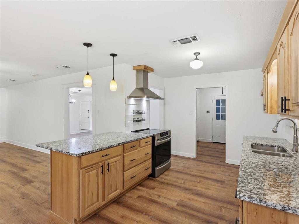 209 Valley View Court Azle, TX 76020 - Photo 10 of 39 Kitchen featuring light stone countertops, stainless steel electric range oven, a kitchen island, dark wood finished floors, and light wood finish cabinetry