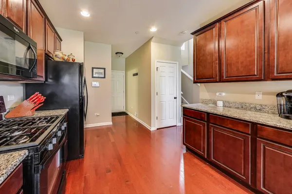 a kitchen with stainless steel appliances granite countertop a refrigerator a sink dishwasher and a stove with wooden floor