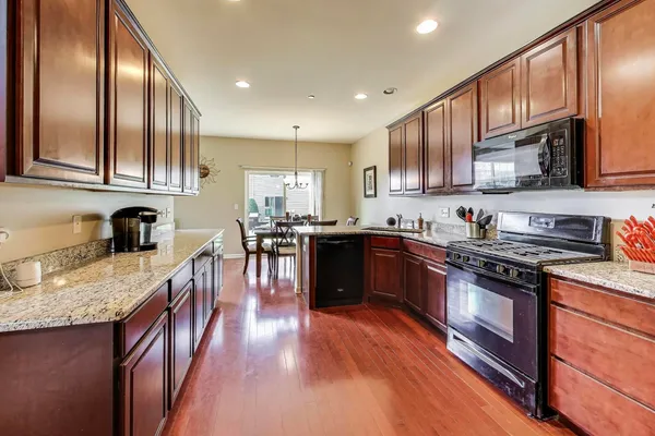 a kitchen with stainless steel appliances granite countertop wooden cabinets a stove top oven a sink and dishwasher