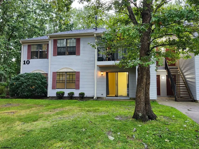a front view of a house with a yard and large tree