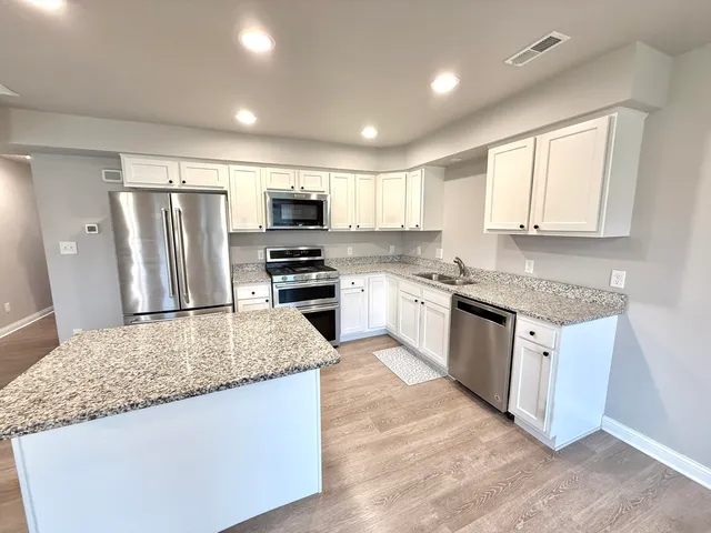 a kitchen with stainless steel appliances granite countertop a sink stove and refrigerator