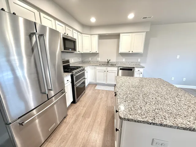 a kitchen with granite countertop stainless steel appliances a refrigerator stove top oven and sink