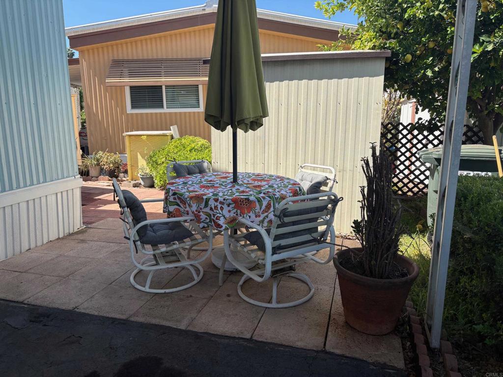 1174 East Main Street, Unit 113 El Cajon, CA 92021 - Photo 17 of 25 a view of a patio with table and chairs potted plants and a palm tree
