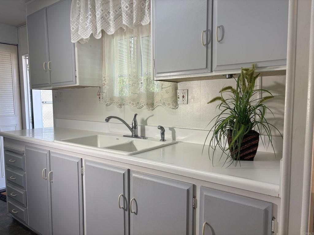 1174 East Main Street, Unit 113 El Cajon, CA 92021 - Photo 2 of 25 a kitchen with a sink a potted plant and cabinets
