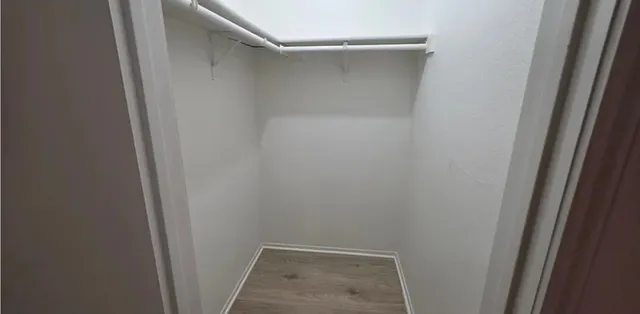 an empty room with wooden floor and a ceiling fan