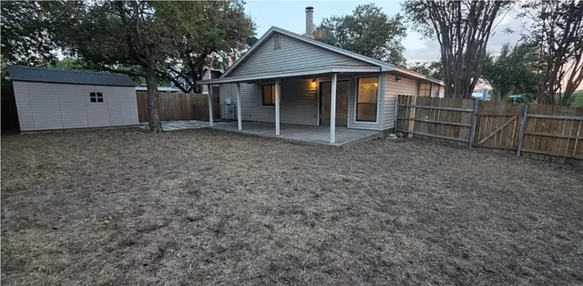 a view of backyard with small cabin and wooden fence