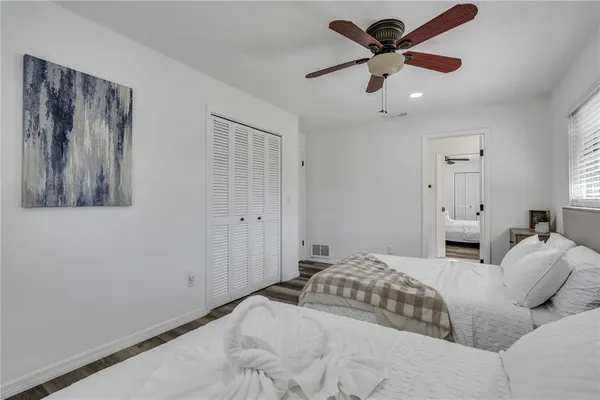 a bedroom with a large bed and a chandelier fan