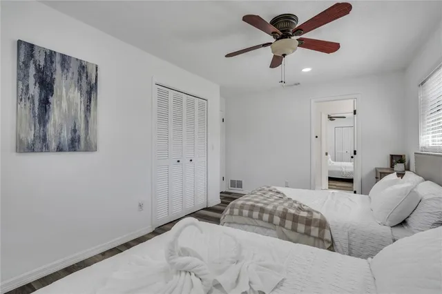 a bedroom with a large bed and a chandelier fan