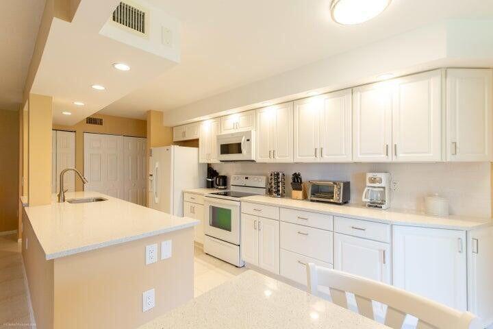110 Half Moon Circle, Unit E2 Hypoluxo, FL 33462 - Photo 2 of 14 a kitchen with granite countertop white cabinets and white appliances
