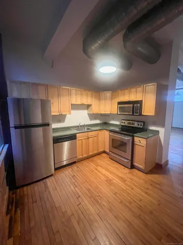 a kitchen with granite countertop a refrigerator and wooden floor