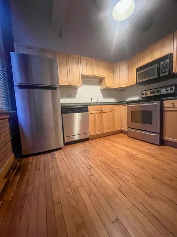 a kitchen with stainless steel appliances wooden floors and wooden cabinets